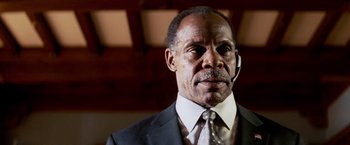 Movie still from “Shooter” (2007), directed by Antoine Fuqua – An older man wearing a suit and tie; Close Up shot, Low angle