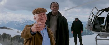 Movie still from “Shooter” (2007), directed by Antoine Fuqua – Two men standing next to each other in front of a helicopter; Medium shot, Over the shoulder angle