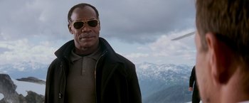 Movie still from “Shooter” (2007), directed by Antoine Fuqua – A man wearing sunglasses standing in front of mountains; Close Up shot, Low angle