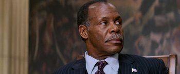 Movie still from “Shooter” (2007), directed by Antoine Fuqua – An older man in a suit and tie looking off into the distance; Close Up shot, Over the shoulder angle