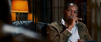 Movie still from “Shooter” (2007), directed by Antoine Fuqua – A man sitting on top of a couch in a living room; Close Up shot, Over the shoulder angle