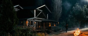 Movie still from “Shooter” (2007), directed by Antoine Fuqua – A log cabin with a porch at night time; Extreme Wide shot, High angle