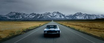 Movie still from “Shooter” (2007), directed by Antoine Fuqua – A car driving down the middle of a road; Wide shot, Low angle