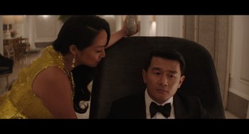 Movie still from “Shortcomings” (2023), directed by Randall Park – A man and a woman sitting in a chair in a room; Medium shot, Over the shoulder angle
