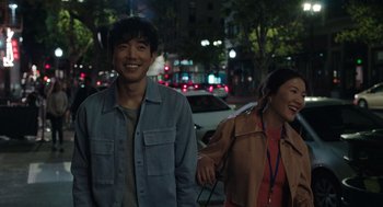 Movie still from “Shortcomings” (2023), directed by Randall Park – A man and a woman walking down a street; Medium shot, Over the shoulder angle