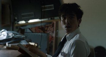 Movie still from “Shortcomings” (2023), directed by Randall Park – A man in white shirt and black tie holding a pencil; Close Up shot, Low angle