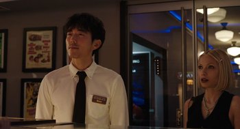 Movie still from “Shortcomings” (2023), directed by Randall Park – A man wearing a white shirt and a black tie; Medium shot, Low angle