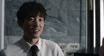 Movie still from “Shortcomings” (2023), directed by Randall Park – A man in a white dress shirt and black tie smiling; Close Up shot, Over the shoulder angle