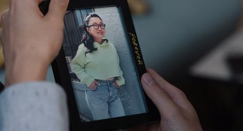 Movie still from “Shortcomings” (2023), directed by Randall Park – A person holding a cell phone in front of a picture; Extreme Close Up shot, Over the shoulder angle