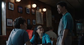 Movie still from “Shortcomings” (2023), directed by Randall Park – A group of people sitting at a table in a restaurant; Medium shot, Over the shoulder angle
