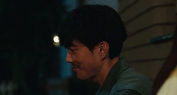 Movie still from “Shortcomings” (2023), directed by Randall Park – A young man with short black hair is smiling; Close Up shot, Over the shoulder angle