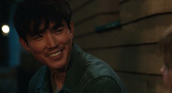 Movie still from “Shortcomings” (2023), directed by Randall Park – A person smiling for the camera; Close Up shot, Over the shoulder angle