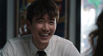 Movie still from “Shortcomings” (2023), directed by Randall Park – A man with a smile on his face; Close Up shot, Over the shoulder angle