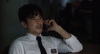 Movie still from “Shortcomings” (2023), directed by Randall Park – A man in a white shirt and black tie talking on a cell phone; Close Up shot, Over the shoulder angle