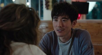 Movie still from “Shortcomings” (2023), directed by Randall Park – A man sitting in front of a woman at a table; Close Up shot, Over the shoulder angle