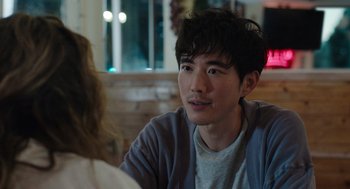 Movie still from “Shortcomings” (2023), directed by Randall Park – A man sitting in front of a woman at a table; Close Up shot, Over the shoulder angle