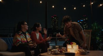 Movie still from “Shortcomings” (2023), directed by Randall Park – A group of people sitting at a table with candles; Medium shot, Over the shoulder angle