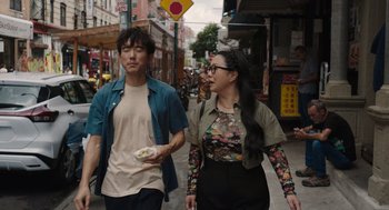 Movie still from “Shortcomings” (2023), directed by Randall Park – A man and a woman walking down a street; Medium shot, Over the shoulder angle