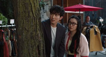 Movie still from “Shortcomings” (2023), directed by Randall Park – A man and a woman standing next to a tree; Medium shot, Over the shoulder angle