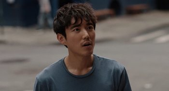 Movie still from “Shortcomings” (2023), directed by Randall Park – A young man with a beard is standing outside; Close Up shot, Over the shoulder angle