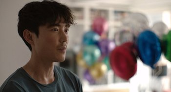 Movie still from “Shortcomings” (2023), directed by Randall Park – A man with a beard is looking to his left; Close Up shot, Over the shoulder angle