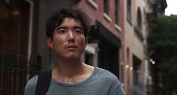 Movie still from “Shortcomings” (2023), directed by Randall Park – A man with a beard is standing in the street; Close Up shot, Over the shoulder angle