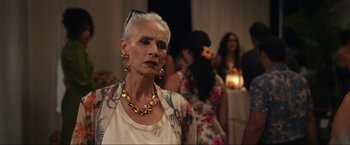 Movie still from “Shotgun Wedding” (2022), directed by Jason Moore – An older woman wearing a floral shirt and a gold necklace; Close Up shot, Over the shoulder angle