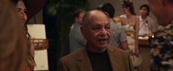 Movie still from “Shotgun Wedding” (2022), directed by Jason Moore – An older man wearing a brown jacket and a brown shirt; Close Up shot, Over the shoulder angle