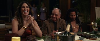 Movie still from “Shotgun Wedding” (2022), directed by Jason Moore – A group of people sitting at a table with a glass of wine; Medium shot, Over the shoulder angle