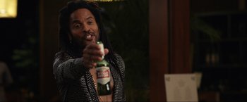 Movie still from “Shotgun Wedding” (2022), directed by Jason Moore – A man with dreadlocks is holding a bottle of beer; Medium shot, Over the shoulder angle