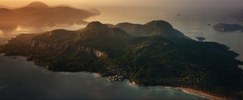 Movie still from “Shotgun Wedding” (2022), directed by Jason Moore – An aerial view of a small town on the coast of a body of water; Extreme Wide shot, High angle