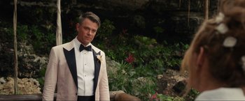 Movie still from “Shotgun Wedding” (2022), directed by Jason Moore – A man in a tuxedo standing in front of some plants; Medium shot, Over the shoulder angle