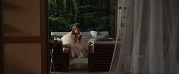 Movie still from “Shotgun Wedding” (2022), directed by Jason Moore – A girl in a white dress sitting on top of a white couch; Wide shot, High angle