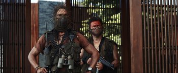 Movie still from “Shotgun Wedding” (2022), directed by Jason Moore – A man with a gun in his hand next to another man with a gun in his other hand; Medium shot, Low angle