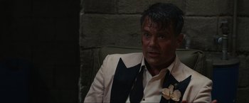 Movie still from “Shotgun Wedding” (2022), directed by Jason Moore – A person sitting in a chair wearing a suit; Close Up shot, Over the shoulder angle