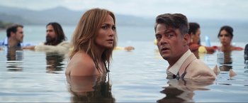 Movie still from “Shotgun Wedding” (2022), directed by Jason Moore – A man and a woman standing in the water in front of a body of water; Medium shot, Over the shoulder angle