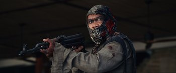 Movie still from “Shotgun Wedding” (2022), directed by Jason Moore – A man with a gun wearing a mask and holding a gun; Close Up shot, Low angle