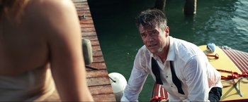 Movie still from “Shotgun Wedding” (2022), directed by Jason Moore – A man sitting on a dock next to a body of water; Close Up shot, Over the shoulder angle