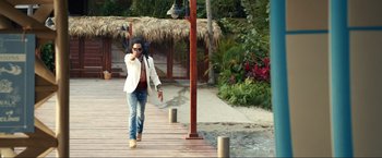Movie still from “Shotgun Wedding” (2022), directed by Jason Moore – A man walking across a wooden pier towards the water; Wide shot, Over the shoulder angle