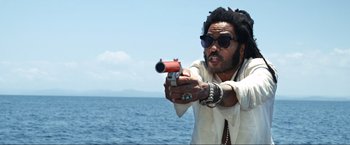 Movie still from “Shotgun Wedding” (2022), directed by Jason Moore – A man holding a gun in front of the ocean; Medium shot, Low angle