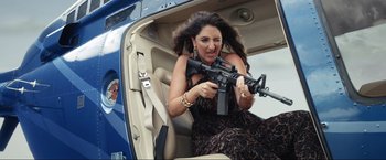 Movie still from “Shotgun Wedding” (2022), directed by Jason Moore – A woman holding an ar - 1 5 rifle while sitting in the back of a car; Medium shot, High angle