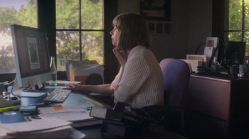 Movie still from “Showing Up” (2022), directed by Kelly Reichardt – A woman sitting at a computer in a room; Medium shot, High angle