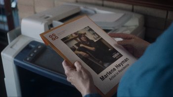 Movie still from “Showing Up” (2022), directed by Kelly Reichardt – A person is holding a book with a picture of a woman; Extreme Close Up shot, Over the shoulder angle