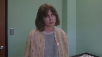 Movie still from “Showing Up” (2022), directed by Kelly Reichardt – A woman with short brown hair wearing a sweater; Medium shot, Over the shoulder angle