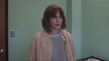 Movie still from “Showing Up” (2022), directed by Kelly Reichardt – A woman with short brown hair wearing a sweater; Close Up shot, Over the shoulder angle