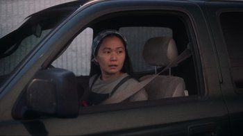 Movie still from “Showing Up” (2022), directed by Kelly Reichardt – A woman sitting in the driver's seat of a car; Medium shot, Over the shoulder angle