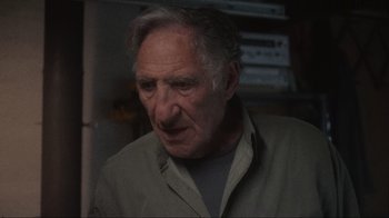 Movie still from “Showing Up” (2022), directed by Kelly Reichardt – An older man with a gray shirt is looking at the camera; Close Up shot, Low angle