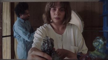 Movie still from “Showing Up” (2022), directed by Kelly Reichardt – A young woman holding a rock in her hands; Close Up shot, High angle