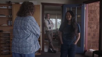 Movie still from “Showing Up” (2022), directed by Kelly Reichardt – Two women and a man standing in front of a door; Wide shot, Over the shoulder angle
