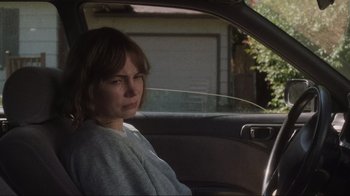 Movie still from “Showing Up” (2022), directed by Kelly Reichardt – A woman sitting in the driver's seat of a car; Medium shot, Over the shoulder angle